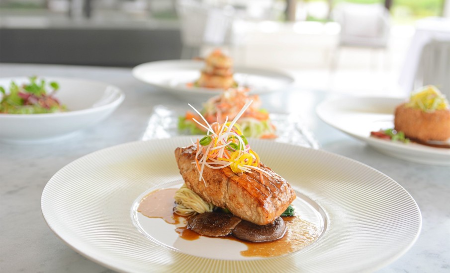 Grilled salmon on a plate garnished with shredded vegetables at Asiatique Asian restaurant in Grenada.