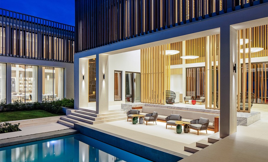 An outdoor lounge with tables and chairs at Silversands Grand Anse shows the exterior of the resort at night.