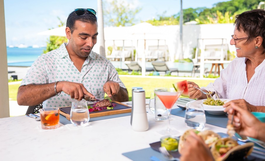 A family enjoying beachfront dining in Grenada at Grenadian Grill at Silversands Grand Anse Resort.