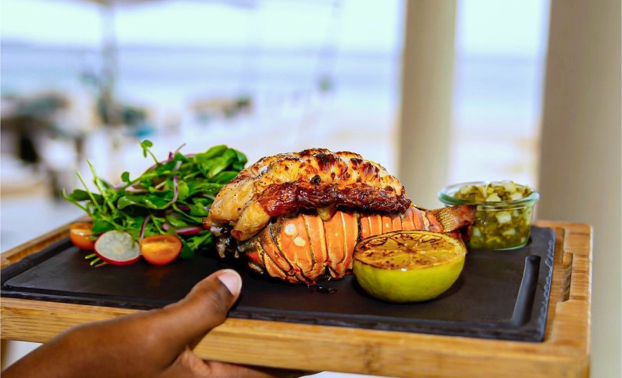 A grilled lobster tail on a plate at Grenadian Grill seafood restaurant in Grand Anse beach.