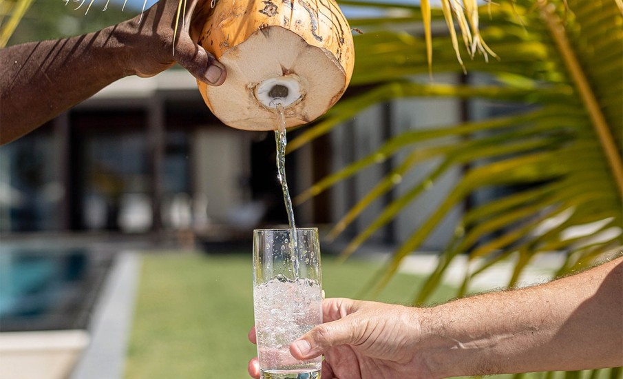 Fresh coconut water being poured into a glass from a coconut at the Beach Lounge in Grand Anse.