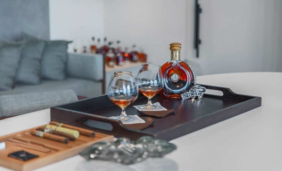A bottle of Cognac with two glasses filled with coganc on a table at Puro bar and lounge at Silversands Grand Anse Resort.