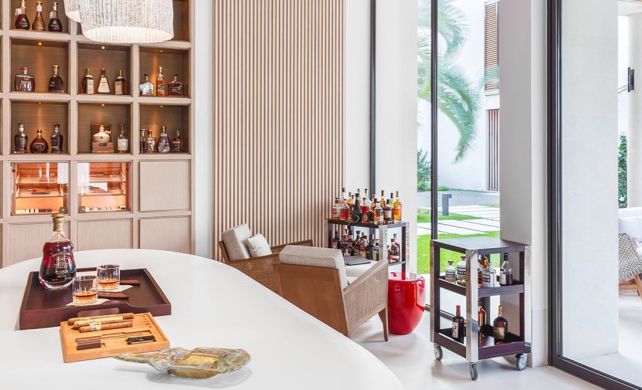 A room with shelves lined with rare Rum bottles and two bar carts filled with bottles of alcohol at Puro at Silversands Grand Anse.