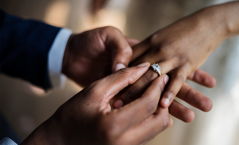 A groom placing the ring on his bride.
