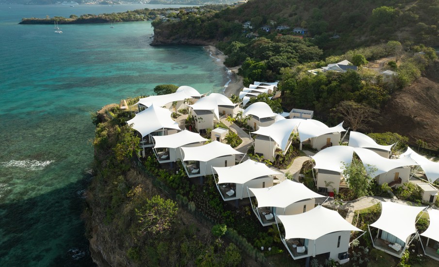 Birds eye view of private suites topped with white canopies on a hilltop overlooking the ocean at Silversands Beach House beach resort in Grenada.