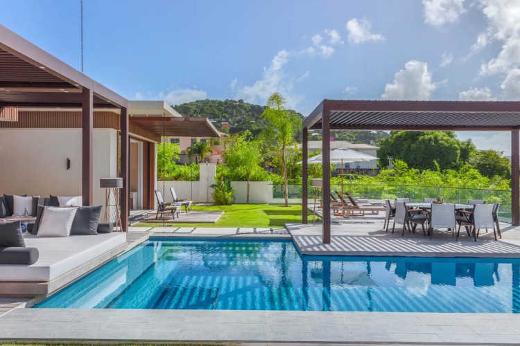 A swimming pool with a deck and chairs at a villa at Silversands resort.