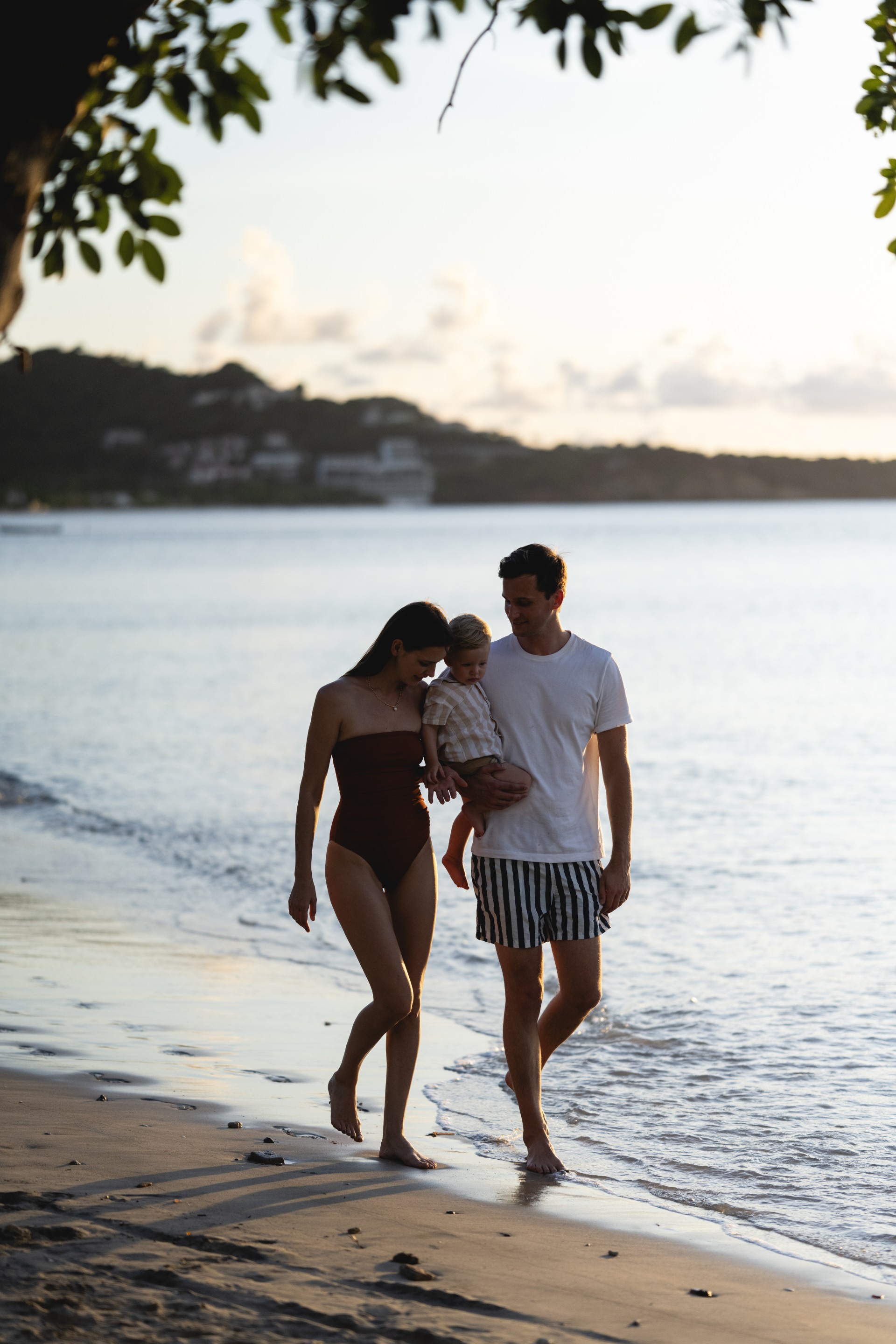 a man and woman holding a baby on a beach