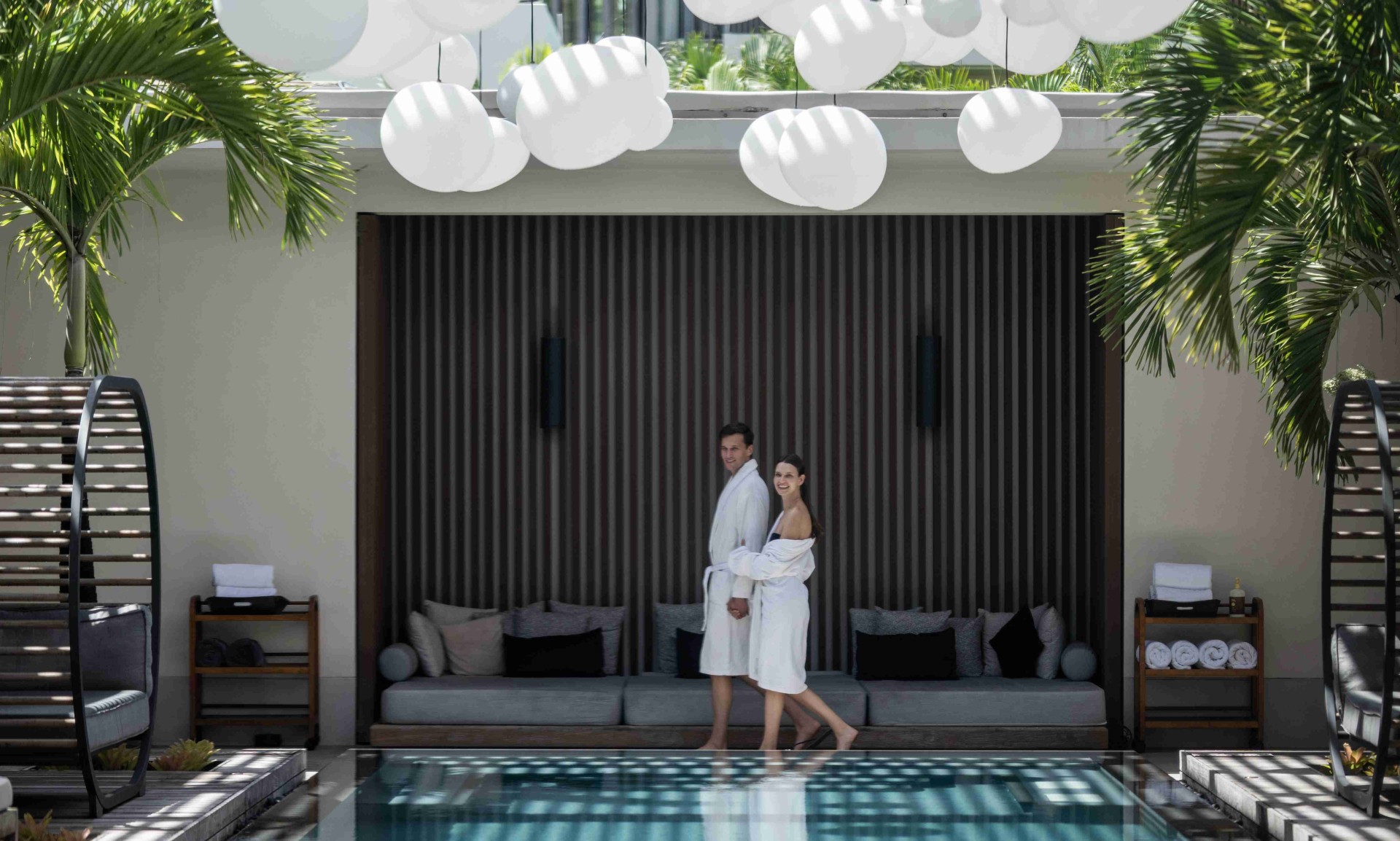 a man and woman in bathrobes standing in front of a pool