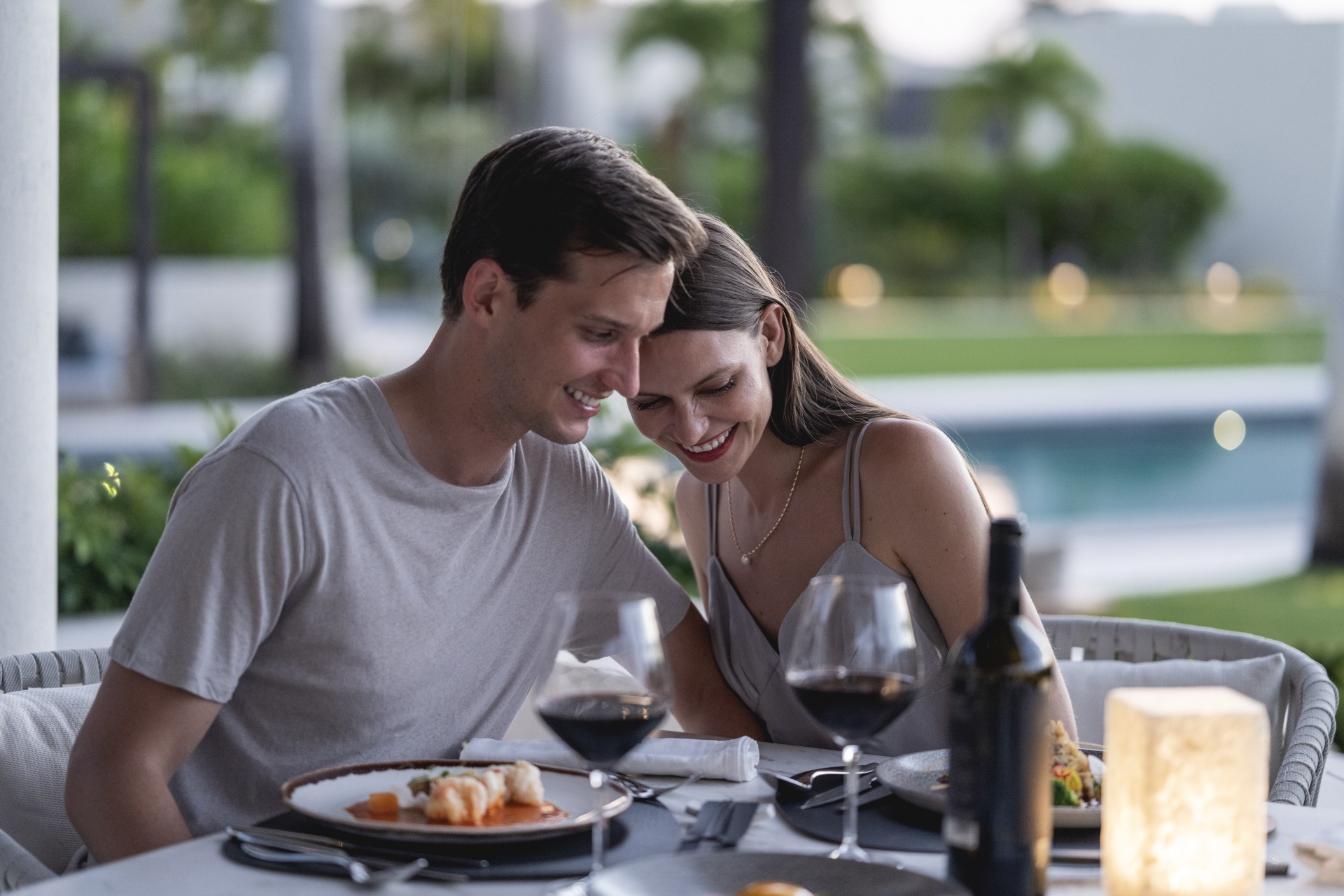 a man and woman sitting at a table with food and wine