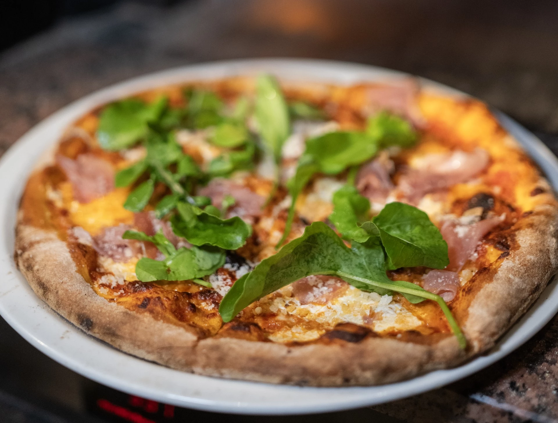 a pizza with greens on a plate