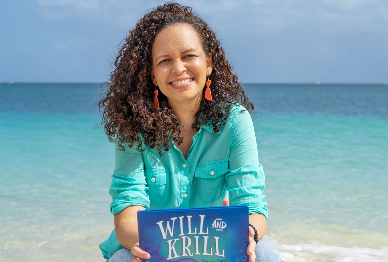 a woman sitting on the beach holding a sign