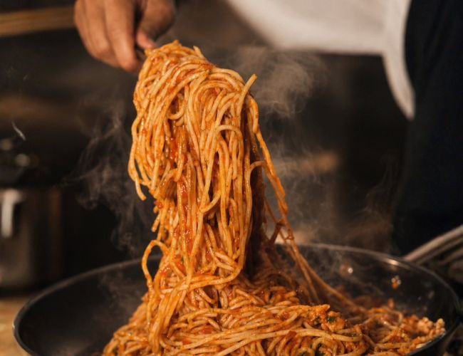a person holding a spaghetti in a pan