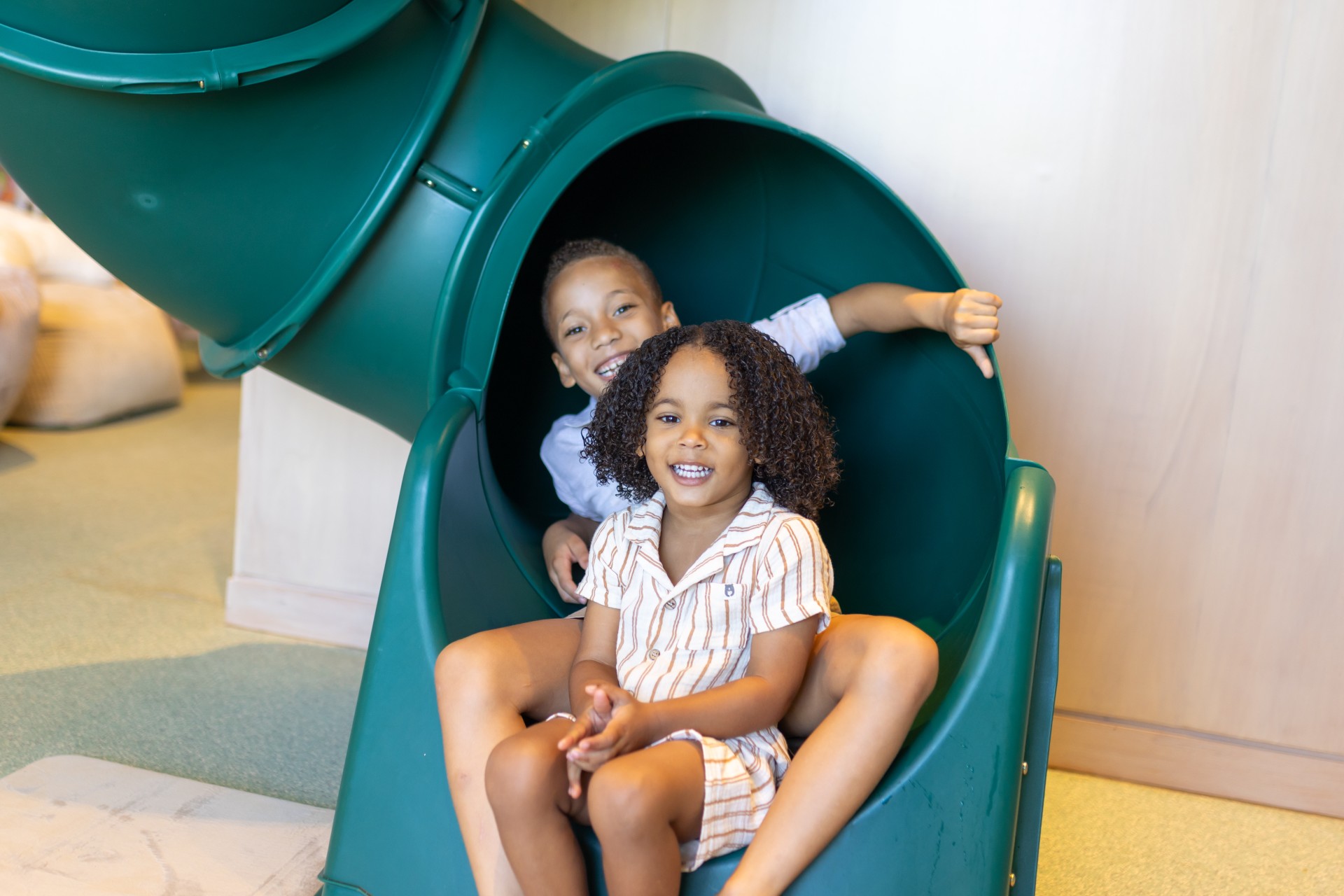 a boy and girl sitting on a slide
