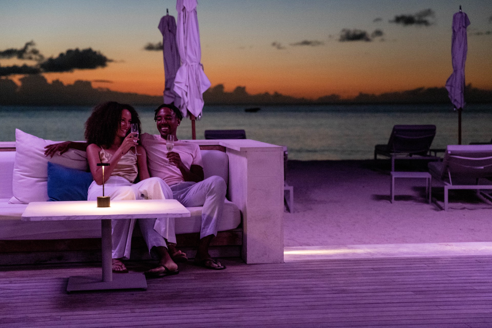 a man and woman sitting on a couch with drinks