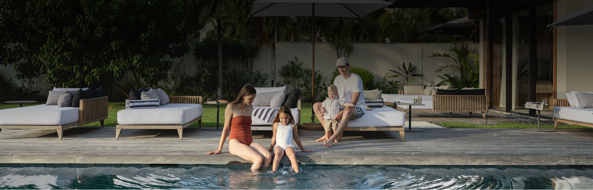 a group of people sitting on a deck with a pool