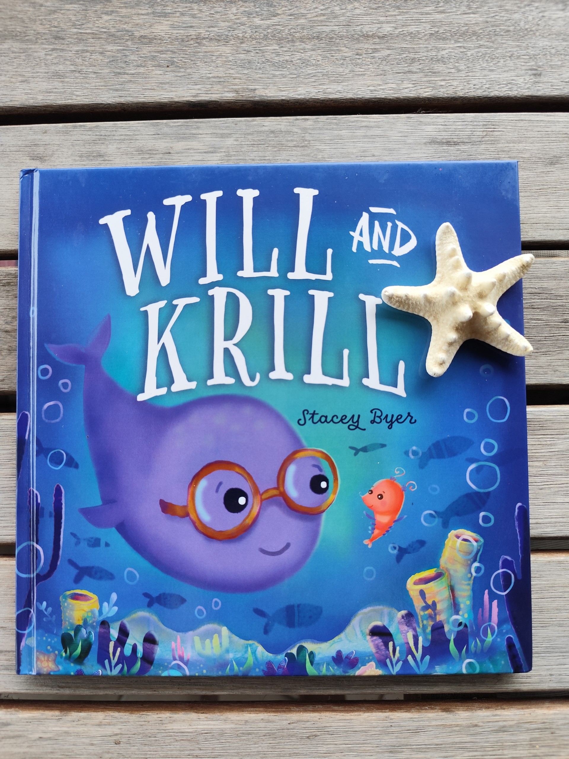 a book with a cartoon whale and a starfish on a wood surface