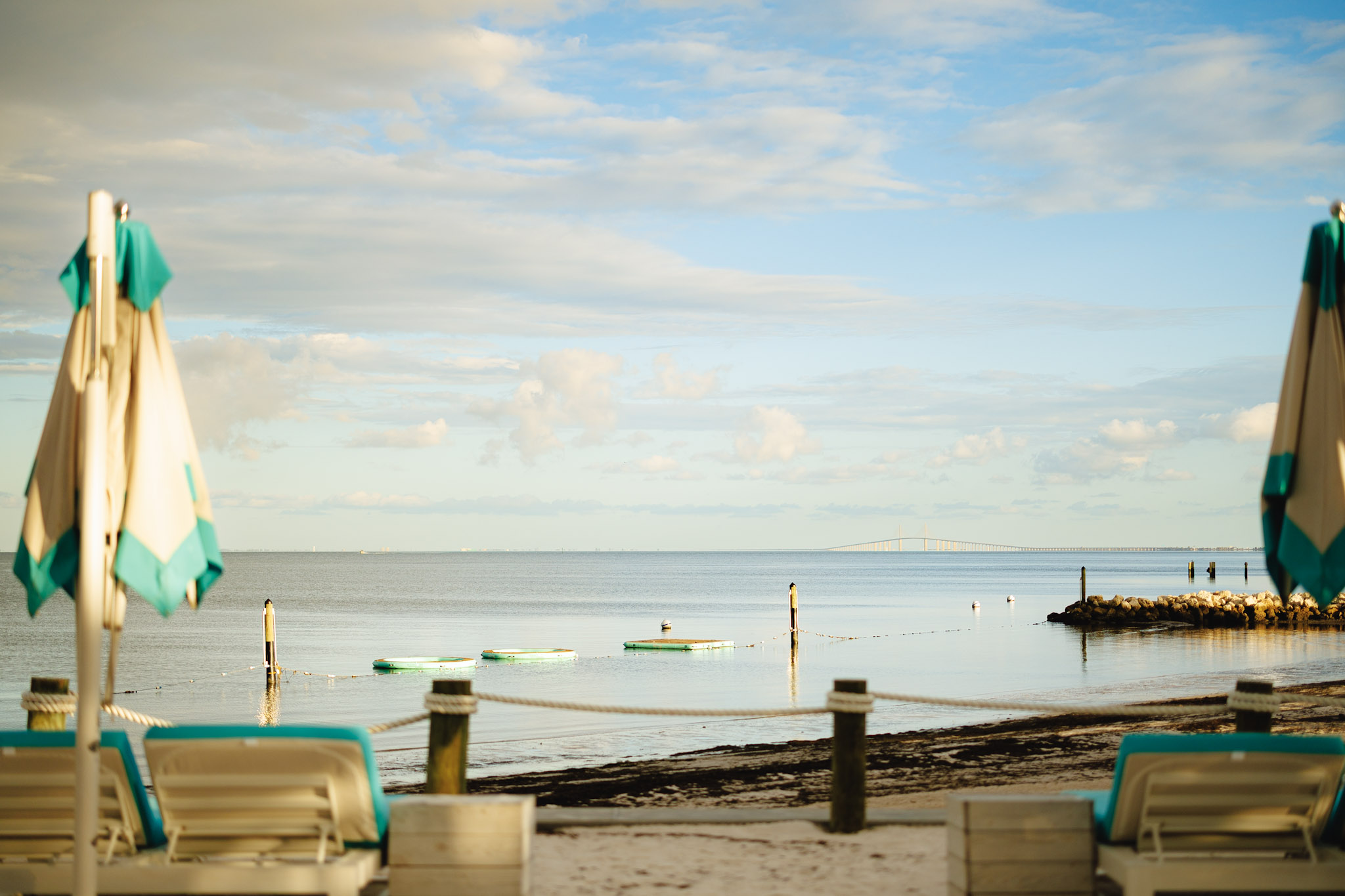 a beach with chairs and boats on the water