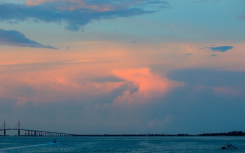 a bridge over water with a pink and blue sky
