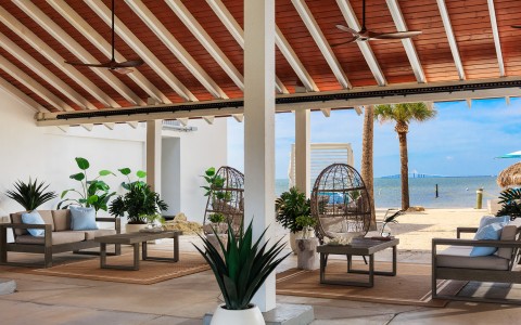 a patio area with chairs and a large fan on the beach