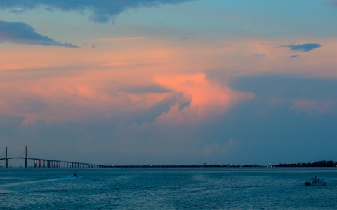 a bridge over water with a pink and blue sky