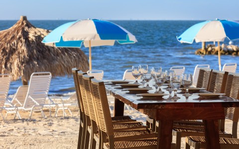 a table with wine glasses and chairs on a beach