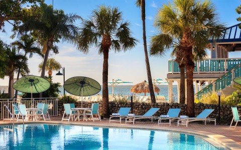 a pool with chairs and umbrellas by a beach
