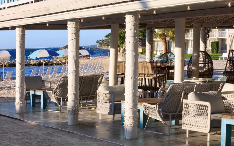 a patio with chairs and tables on the beach