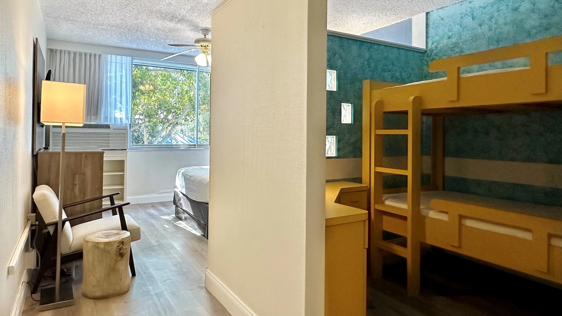 A room with bunk beds, a desk, chair, and lamp.