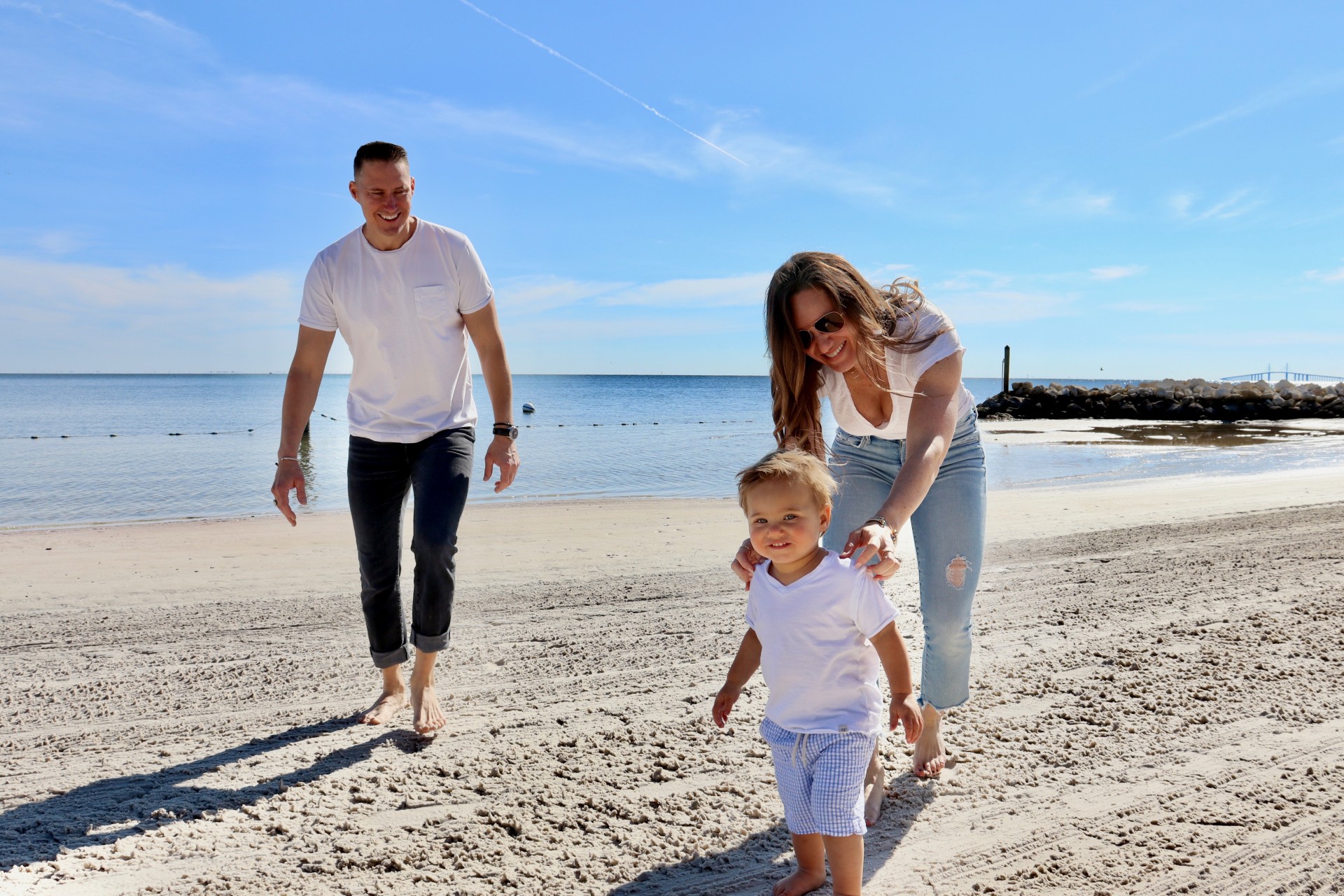 a man and woman walking with a baby on a beach