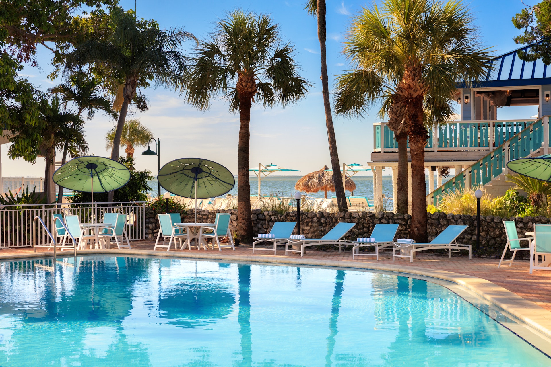 a pool with chairs and umbrellas by a building
