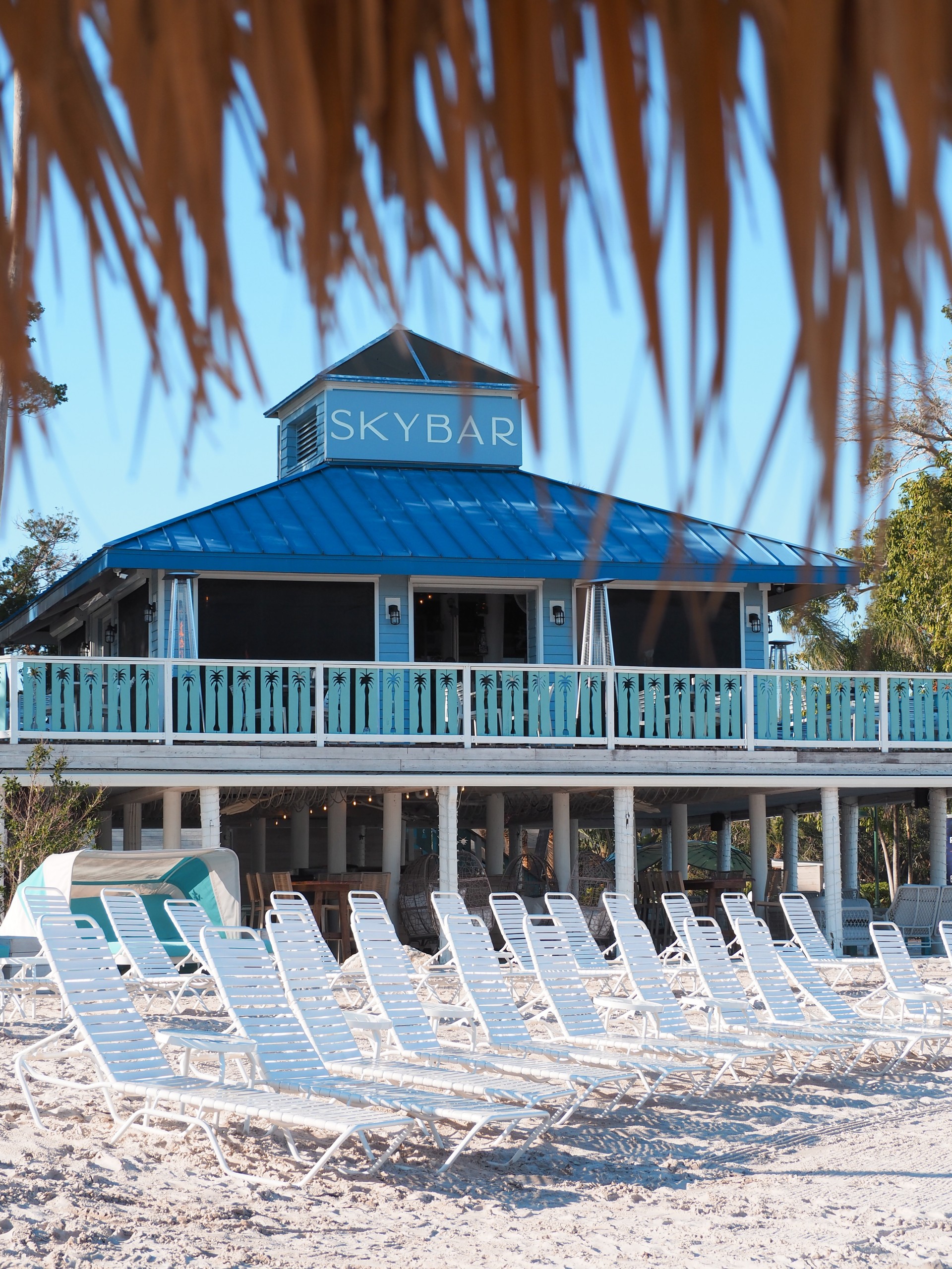 a building with a deck and chairs on the beach