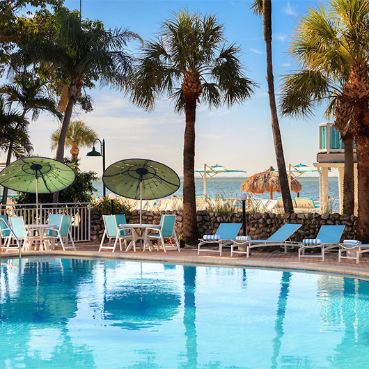 a pool with chairs and umbrellas by a beach