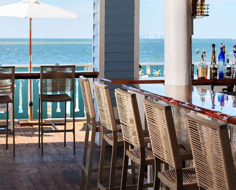 a bar with chairs and bottles of alcohol on the deck