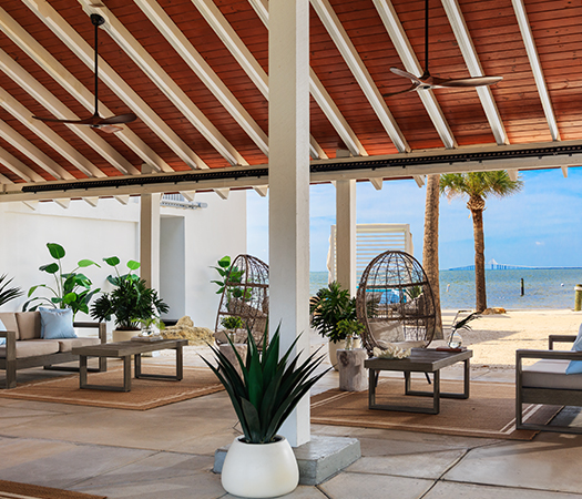 a patio area with chairs and a fan on the beach