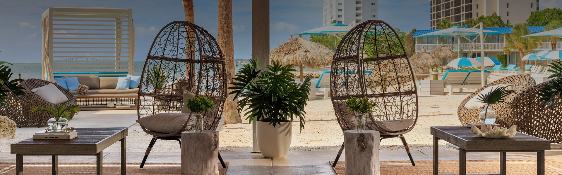 A beachside seating area with wicker furniture and plants.