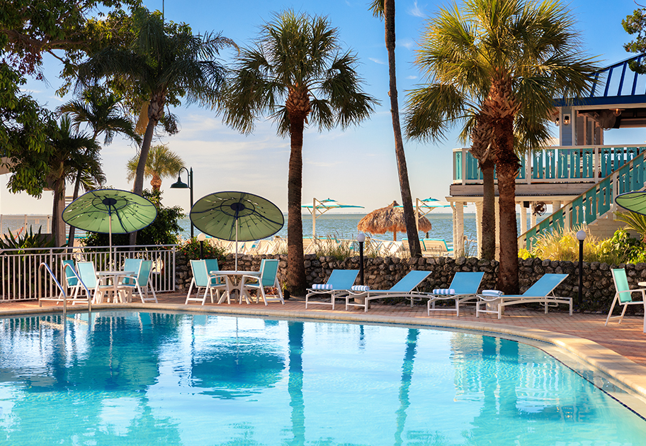 a pool with chairs and umbrellas by a beach