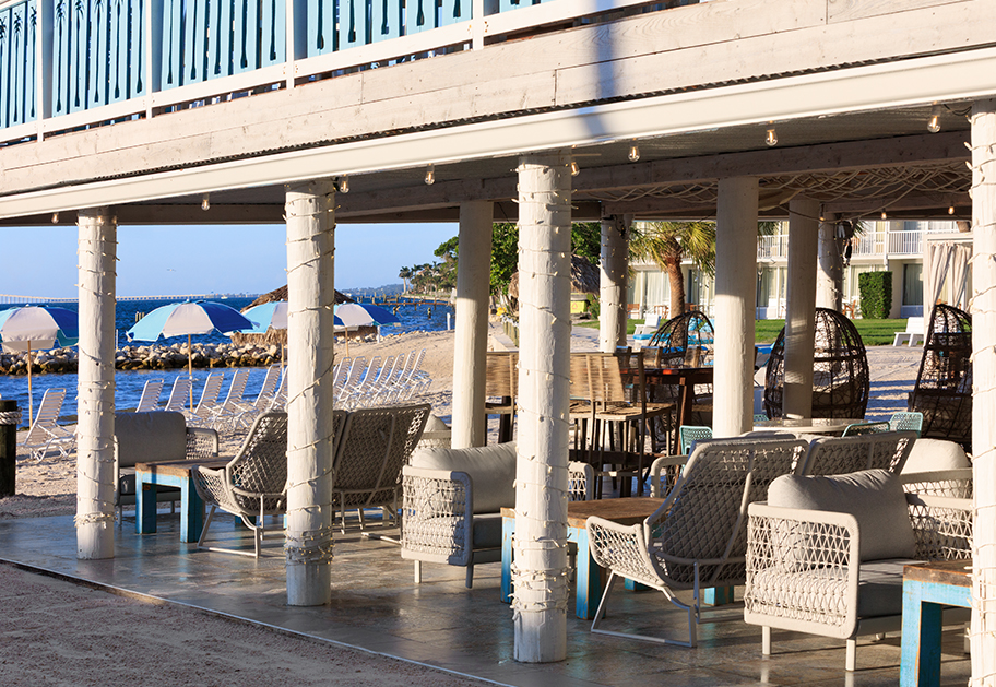 a patio with chairs and tables on a beach