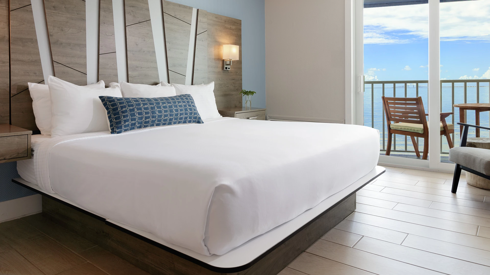 A hotel room with a large bed, wooden headboard, and balcony with a view.