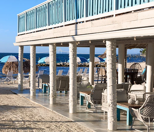A beachside patio with white columns and blue accents overlooking the ocean.