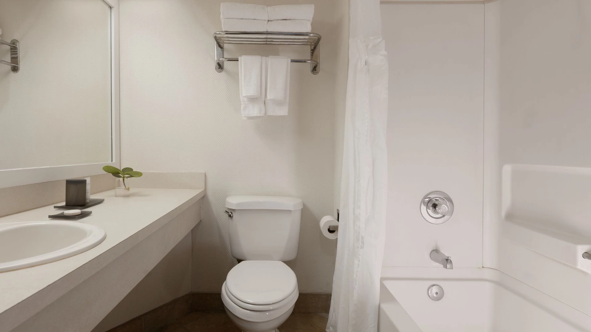 A clean and modern bathroom with a toilet, sink, bathtub, and mirror.