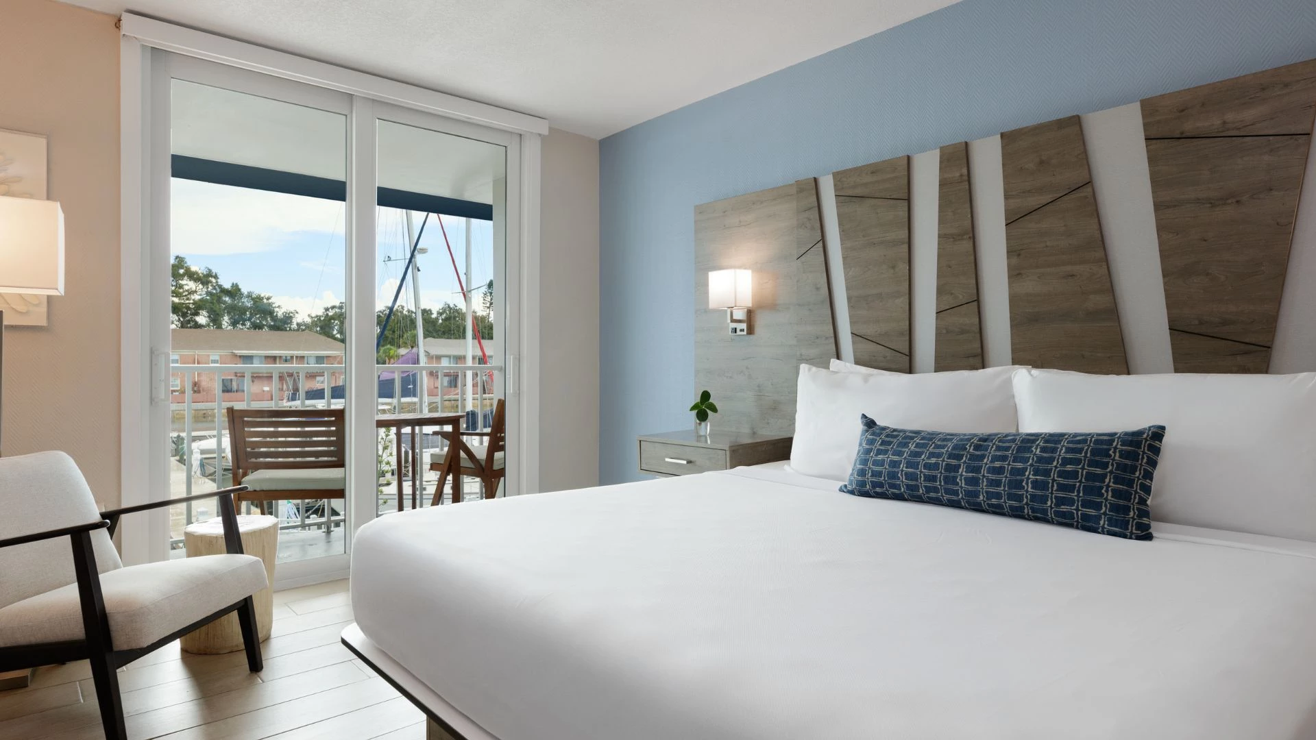 A hotel room with a large bed, chair, and balcony