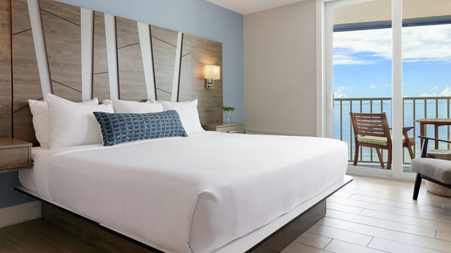 A hotel room with a large bed, balcony, and ocean view.