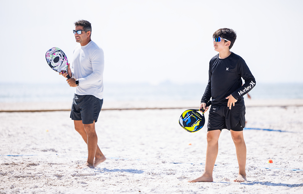 a man and boy holding paddles on a beach
