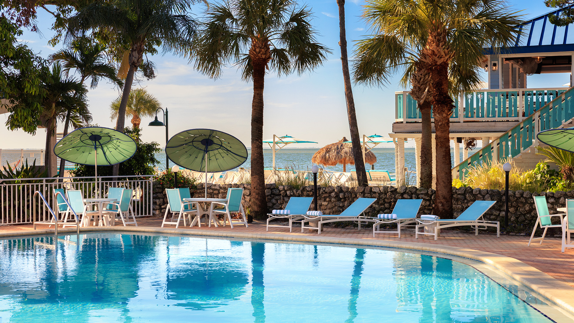 a pool with chairs and umbrellas by a beach