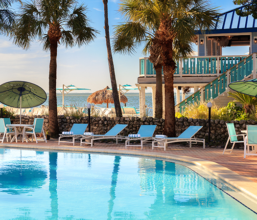 a pool with lounge chairs and umbrellas by a building