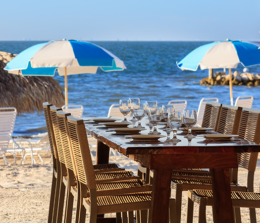 a table with wine glasses and chairs on a beach