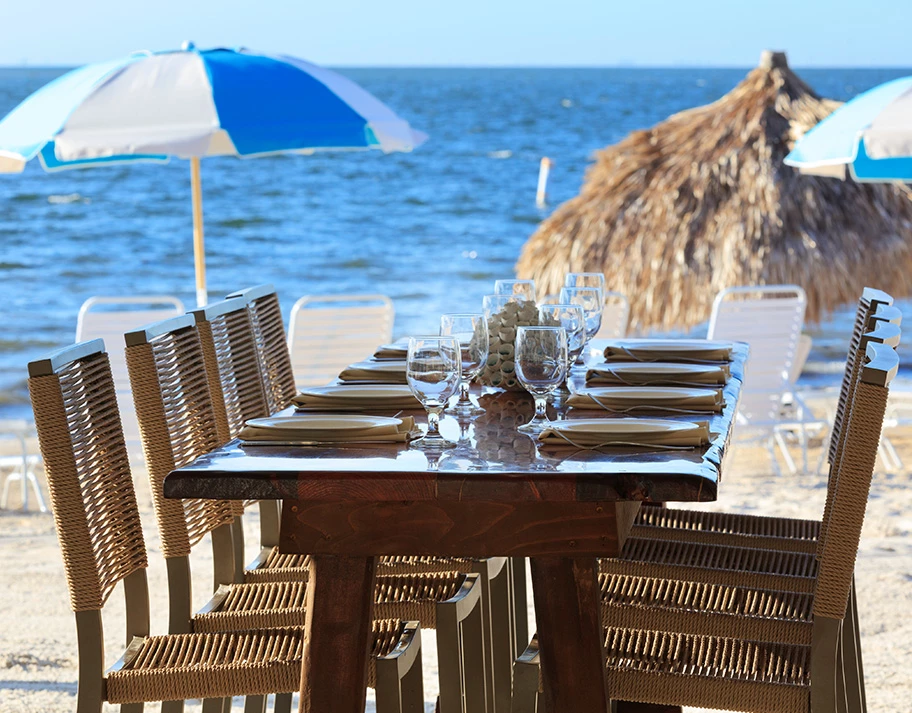A table set for dining on the beach with a view of the ocean.