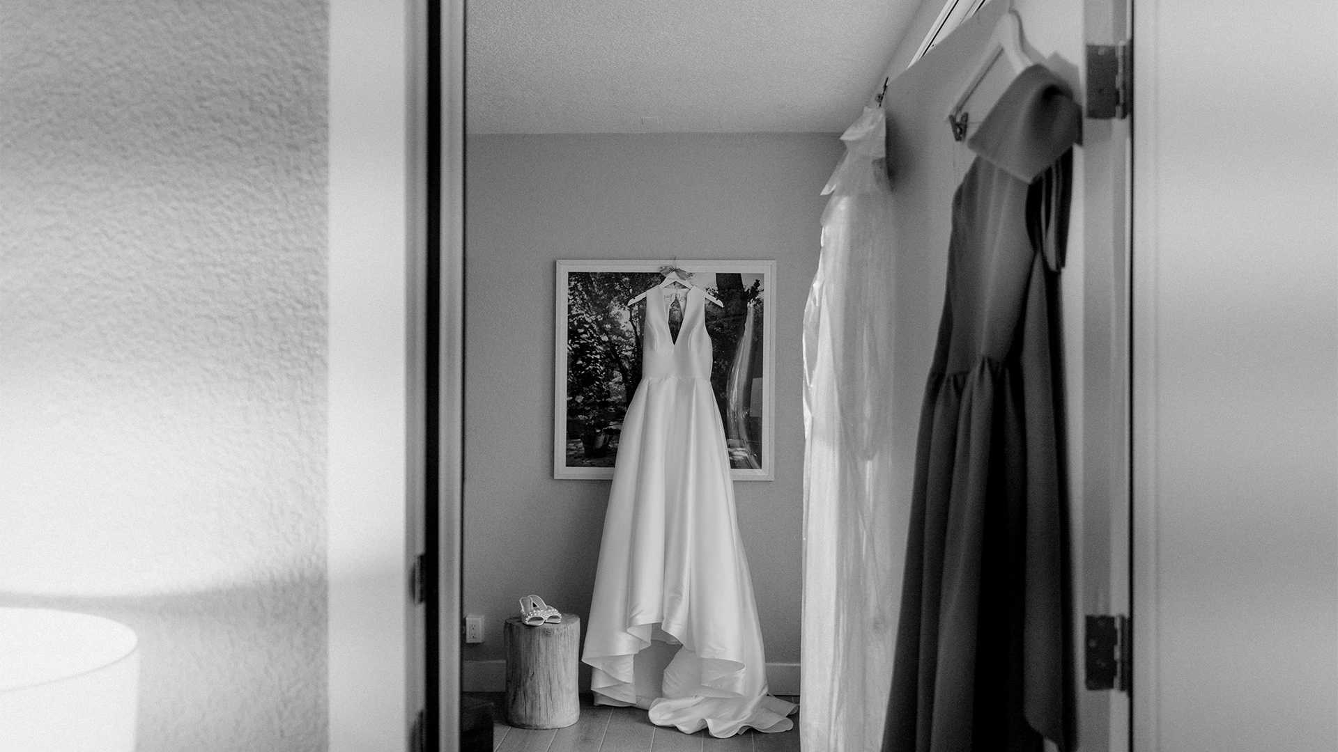 A black and white photo of a doorway with dresses hanging inside.