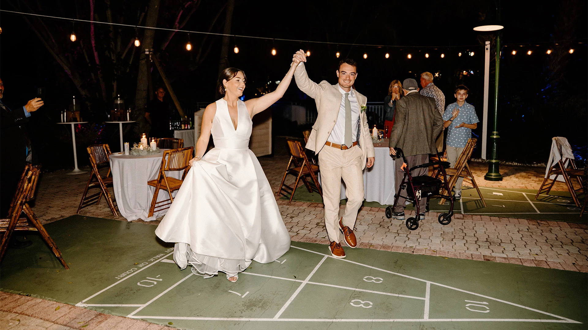 A bride and groom dancing on an outdoor patio at night.