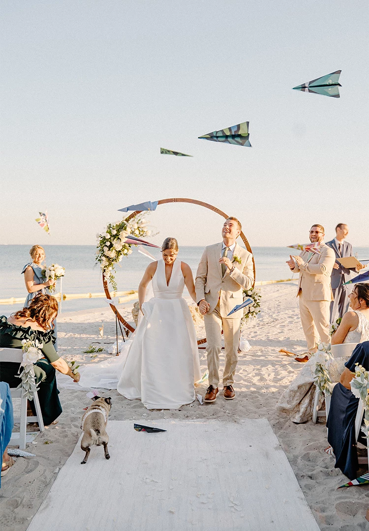 A beach wedding ceremony with a couple under an archway.